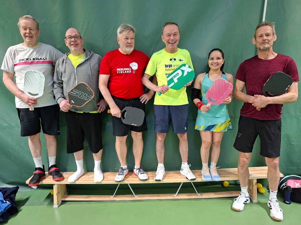 Winners of the Three Cities Pickleball Doubles Tournament on the podium holding their paddles